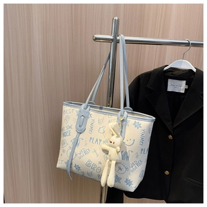 Detail of minimalist tote bag with blue graffiti print and cute plush bunny charm