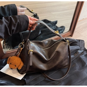 Detail view of dark coffee leather tote with gold hardware and plush teddy pendant