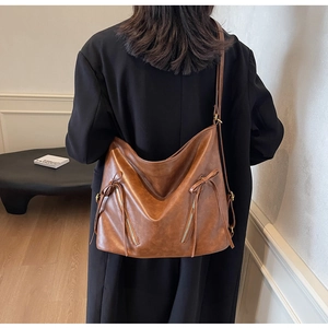 Detail of vintage brown large capacity shoulder bag with double zipper and bow decor