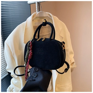 Détail du sac bowling noir en daim avec double fermeture éclair et accessoires dorés