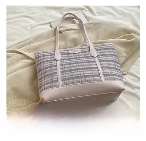 Detail show of pink plaid tote bag with faux leather straps on cozy fabric background