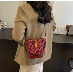 Dettaglio della borsa a secchiello leopardata con finiture in pelle bordeaux e fibbia d'oro