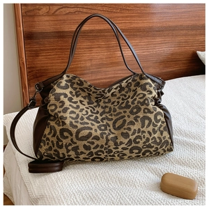 Detail of leopard print tote bag with brown leather handles and adjustable straps