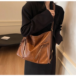 Detail of vintage brown leather tote bag with decorative side zippers and bow knot