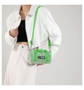 Detail of light green corduroy cylinder bag with textured fabric and crossbody strap