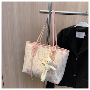 Detail of off-white tote bag with pink graffiti letters and a cute plush rabbit charm