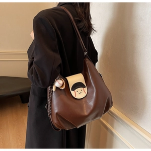 Detail of hobo bag with baseball charm and cartoon character design in dark brown finish