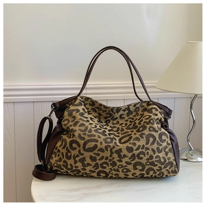 Detailed view of leopard print tote bag with brown leather straps on a white table