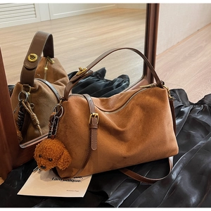 Detailed macro of brown suede tote bag with golden hardware and teddy bear charm accessory