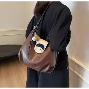Detailed view of brown leather hobo bag with baseball smiley flap and cute charms