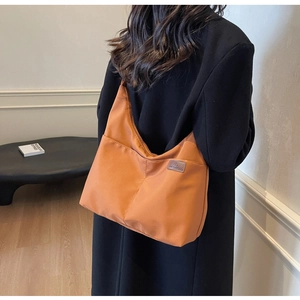 Détail du sac cabas en nylon caramel montrant l'étiquette mode et la texture imperméable