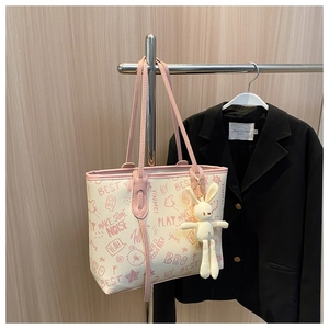 Detail of cream tote bag with pink graffiti prints and cute plush rabbit charm