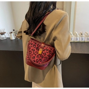 Dettaglio della borsa a secchiello leopardata rossa con chiusura dorata sulla modella