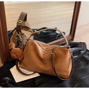 Close-up of brown suede tote bag with vintage metal lock and plush puppy charm