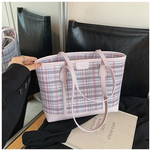 Detail of pink plaid tote bag with faux leather handles and brand logo tag on seat