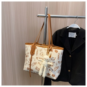 Detail of white graffiti tote bag with brown leather trim and cute rabbit doll pendant