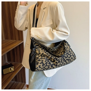 Close-up of leopard print tote bag fabric with black leather shoulder strap and trim