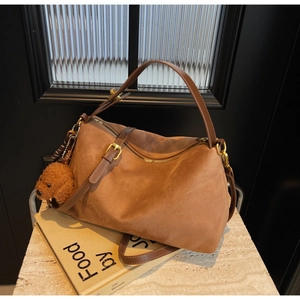 Detail of brown suede tote bag with leather handles and cute teddy bear plush charm