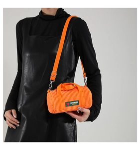 Detail of orange corduroy mini cylinder bag with silver hardware and adjustable strap