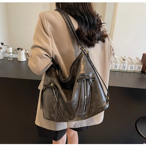 Detail of vintage large capacity shoulder bag with decorative bow zippers and matte texture