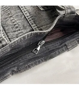 Detailed close-up of smooth metal zipper and dense double-row stitching on charcoal denim tote
