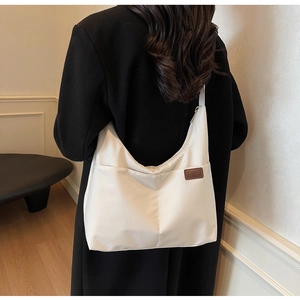 Détail d'un sac cabas crème avec étiquette en cuir marron et bandoulière large