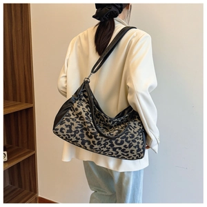 Large leopard print hobo bag with adjustable wide shoulder strap shown on a model