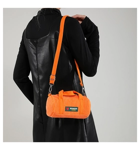 Detail of orange corduroy barrel bag with adjustable strap and heart patch on model