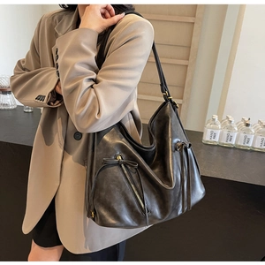 Detail of vintage large capacity black hobo bag on model showing draped texture and metal zips