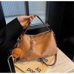 Brown suede hobo bag featuring a cute poodle plush charm and adjustable shoulder strap