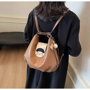 Detail of soft brown leather backpack with baseball motif and decorative pendants