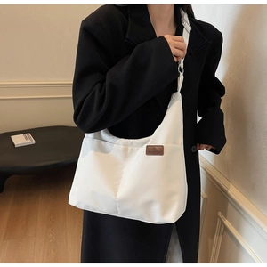 Détail du grand sac cabas blanc avec étiquette en cuir marron et bandoulière réglable