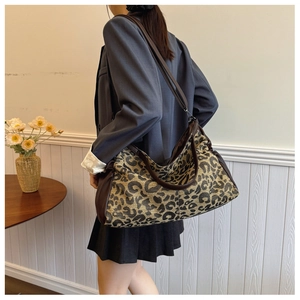 Close-up of leopard print tote bag with brown leather handles and dual strap details
