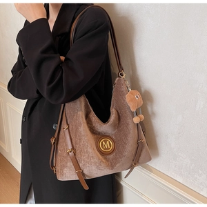 Detail of vintage brown velvet tote bag with metal M logo and cute bear charm