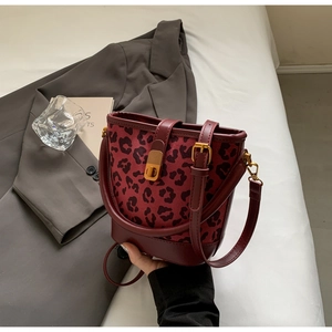 Dettaglio della borsa a secchiello bordeaux con stampa leopardata tenuta da una modella