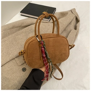 Détail du sac bowling vintage en daim marron avec porte-clés doré et accents tissés