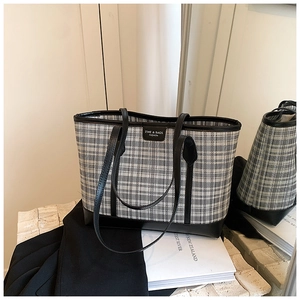 Detailed view of checkered tote bag with black leather trim and metal brand logo plaque