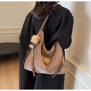 Brown velvet hobo shoulder bag with leather trim and bear pendant on a model