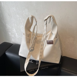 Détail d'un sac cabas blanc cassé avec étiquette en cuir marron et détails de sangle