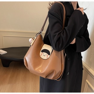 Detail of brown PU leather tote bag featuring baseball smiley flap and cute charms