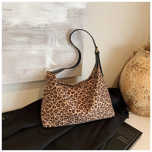 Detail der Hobo-Tasche mit Leopardenmuster, Lederriemen und goldener Schnalle auf Sakko