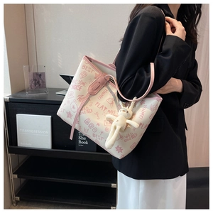 Detail of graffiti tote bag with pink trim and cute white bunny plush pendant charm