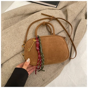Détail d'un sac bowling rétro marron mat avec lettrage gaufré et breloque clé
