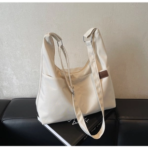 Détail d'un sac fourre-tout en toile crème posé sur une surface en cuir noir