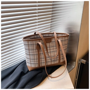 Detail of vintage plaid tote bag with brown leather trim and fashion logo plaque