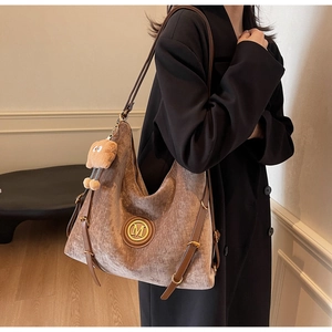 Detail view of taupe velvet tote bag with golden metal M logo and plush pendant