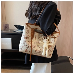 Detail of a large tote bag with graffiti prints and a cute rabbit doll charm on the side