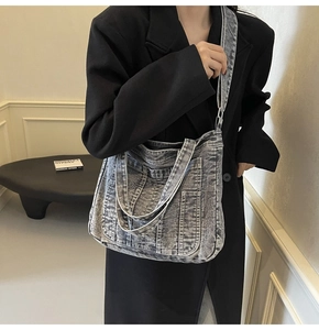 Detail of grey washed denim tote bag showing pockets, heavy fabric texture and shoulder strap