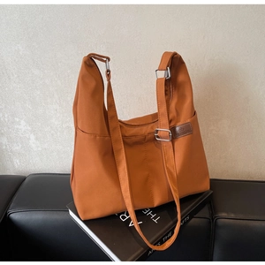 Détail latéral du sac cabas en nylon caramel avec boucle argentée et poche latérale