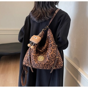 Detail of leopard print tote bag with golden M logo and brown plush toy charm